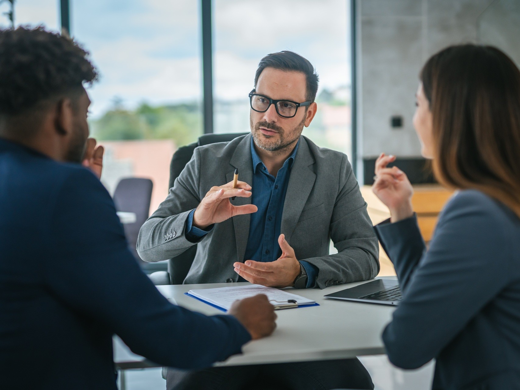 Financial adviser discussing contract with diverse couple in office meeting