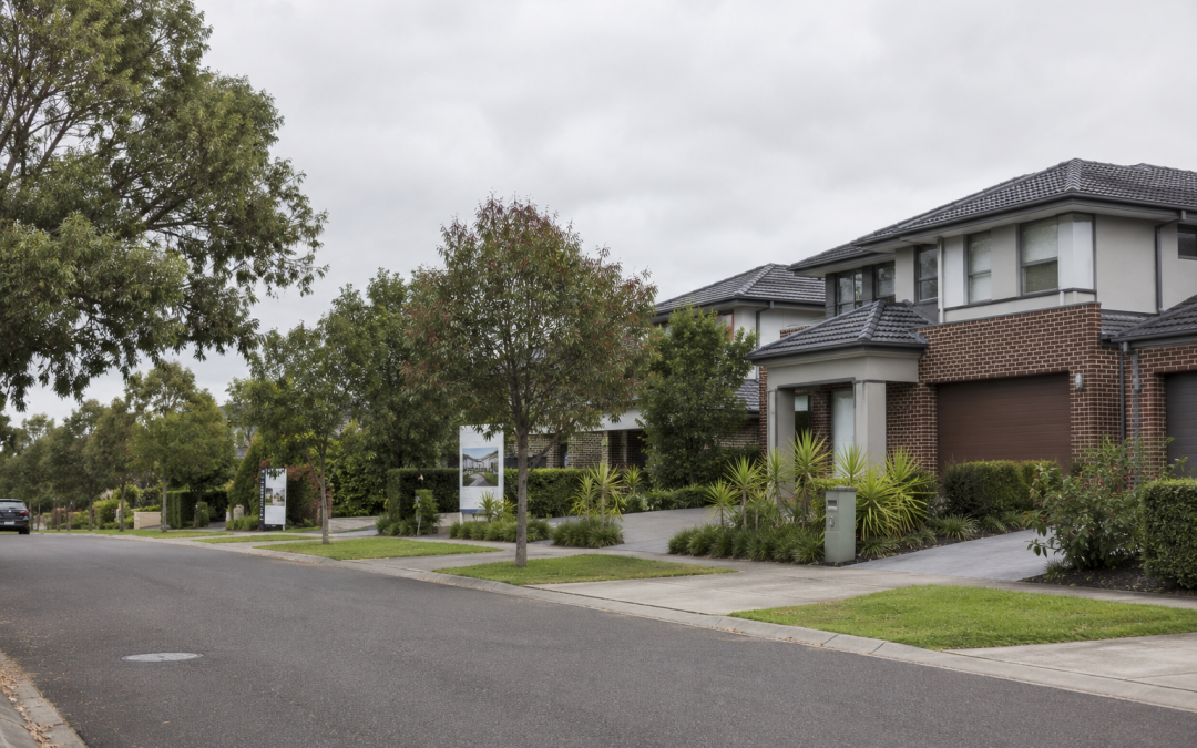 Established Australian suburban street with a property for-sale board on an overcast day